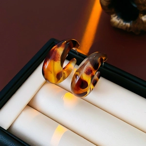 Macro shot of leopard print resin C-shaped hoop earrings in a premium jewelry box