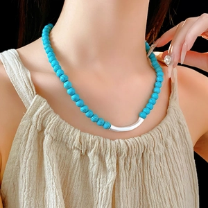 Collier en perles turquoise avec tube argenté, présenté sur le cou d'un mannequin