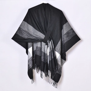 Detail view of monochrome plaid shawl poncho featuring fringe trim and soft wool texture
