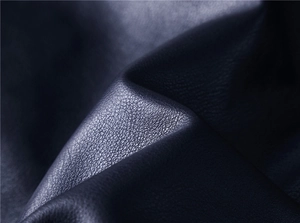 Close-up of black PU leather fabric showing detailed grain texture and soft glossy finish