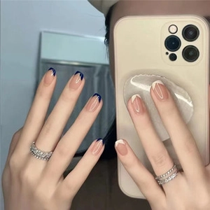 Detailed view of long French style navy blue and white press-on nails on model hands