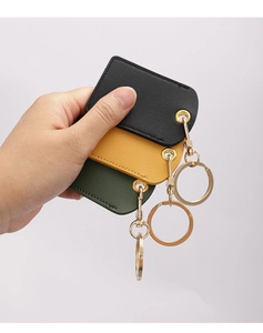Leather keychains in black, yellow, and green colors with gold rings held in hand