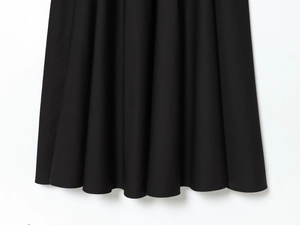 Close-up of the pleated hem and fabric texture of a black long business blazer dress