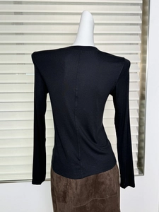 Back view of black long-sleeve knit top with shoulder pads and slim fit silhouette