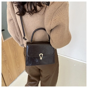 Brown PU leather crossbody bag with gold buckle shown on model in casual winter outfit