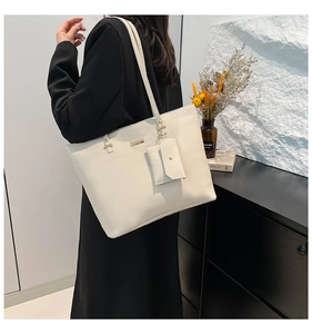Detailed view of white litchi pattern leather tote bag with a small matching pouch