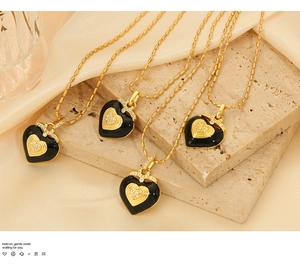 Close-up of heart-shaped black enamel necklaces with gold beads and crystals on silk