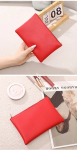 Macro detail of red lychee pattern PU leather makeup bag featuring a silver metal zipper