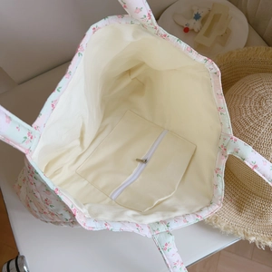 Detail of pink floral quilted tote bag featuring a spacious interior and a zippered pocket