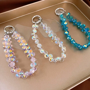 Close-up of pink, iridescent, and blue faceted crystal phone chains on a gold tray