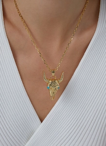 Golden bull skull necklace with blue turquoise eyes on a model wearing white clothes