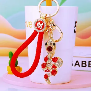 Detail of snake keychain with sparkling rhinestones, golden alloy, and red woven strap