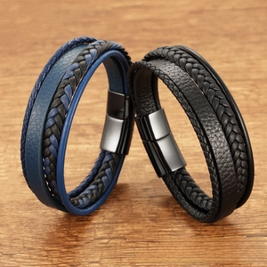 Detail of multi-layer woven leather bracelets with magnetic clasps on wood background