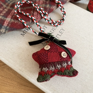 Macro detail of star-shaped Christmas plush ornament with red knit and wooden buttons