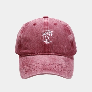 Detailed close-up of a burgundy washed cotton baseball cap with white coconut tree embroidery