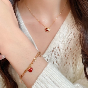 Detail of gold plated necklace and bracelet set with red heart and bear pendants