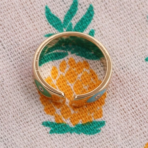 Gold plated open ring featuring blue and green enamel evil eye charms on textured fabric