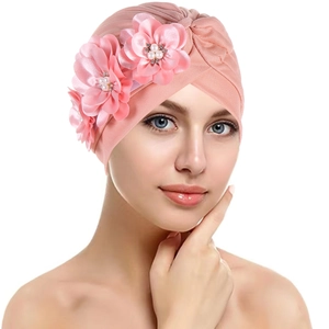 Detail of pink pleated turban hat featuring silk flowers and pearl embellishments