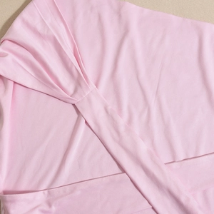 Close-up of pink knit fabric featuring a twist knot detail and cross-wrap design