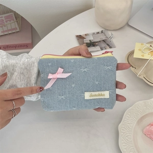 Dettaglio della borsa in denim con fiocco di seta rosa ed etichetta Sezakka in mano