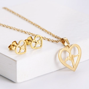 Parure collier pendentif cœur battant et boucles d'oreilles dorés sur bois blanc