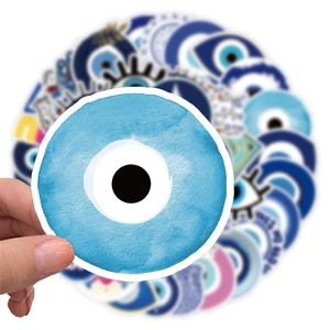 Macro detail of a hand holding a round blue evil eye sticker from a 50-piece waterproof set
