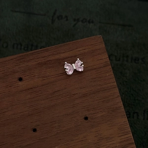 Macro view of pink marquise zircon butterfly earring on a rustic wooden display