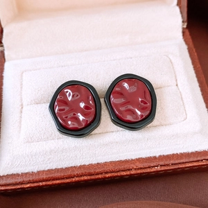 Close-up of vintage irregular pleated earrings with deep red core and black geometric border