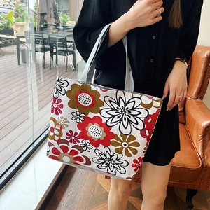Large floral canvas tote bag with gray straps shown in a warm lifestyle indoor setting