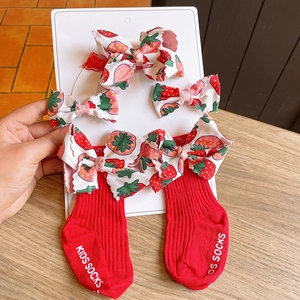 Detail of red strawberry bow hair clips and ribbed socks set on display card