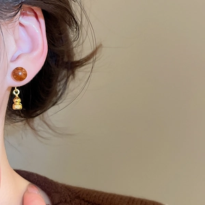 Gros plan de boucles d'oreilles vintage en résine ambre et gourde dorée sur un modèle