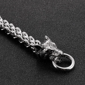 Detailed close-up of a silver wolf head buckle on a braided metal chain bracelet