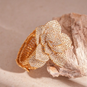 Macro detail of gold flower cuff bracelet with sparkling zircon stones on stone