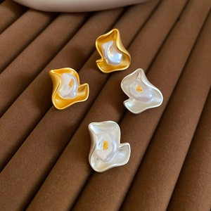 Macro shot of irregular floral earrings with gold leaf embedded in pearls on velvet