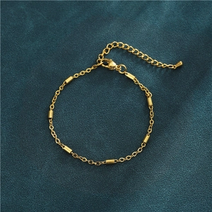 Detailed view of golden 304L stainless steel bracelet with cylindrical beads on teal velvet
