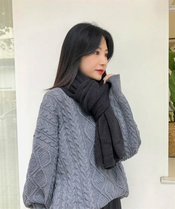 Detailed texture of black cable knit scarf paired with a grey winter knitted sweater