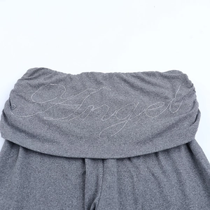Détail du pantalon gris en maille avec taille rabattue et lettrage Angel en strass brillant