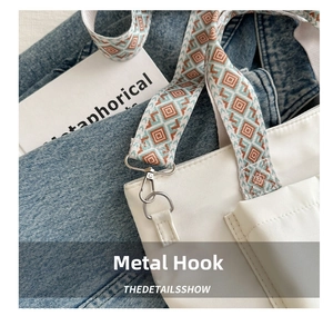 Detail of high-quality silver metal hooks and colorful woven strap on a white tote bag