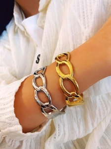 Close-up of thick gold and silver link bracelets worn on a wrist for a modern look