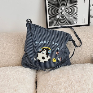 Close-up of cute dog embroidery on blue and white striped canvas shoulder bag on sofa