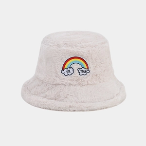 Détail d'un chapeau bob en peluche beige avec broderie arc-en-ciel et texte 'OH YEAH!'