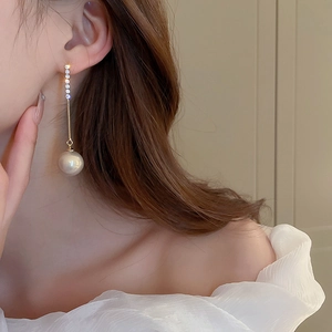 Close-up of model wearing long pearl tassel earrings with shimmering crystals