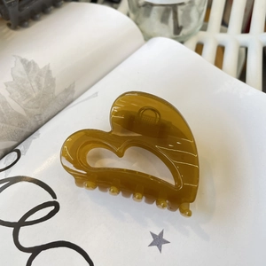 Détail d'une pince à cheveux cœur ambre sur des pages de livre avec texture brillante