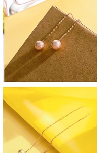 Dettaglio macro di orecchini a catenella oro rosa con sfere satinate effetto polvere