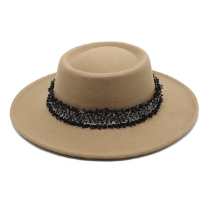 Detalle de sombrero de lana camel con banda de tweed en blanco y negro con flecos