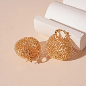 Close-up of gold geometric mesh hoop earrings with intricate metallic woven texture