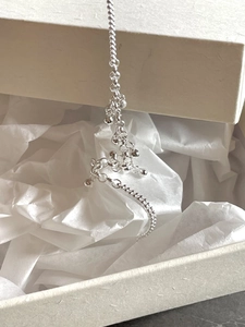 Close-up of a 925 sterling silver beaded bracelet hanging over a gift box edge
