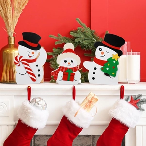 Detailed view of three festive wooden snowmen figurines on a white fireplace mantel