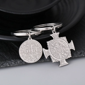 Detail of silver stainless steel Saint Benedict medal and cross charms on keychains