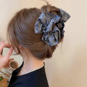 Elegant large grey fabric hair claw clip with black bow pattern on a model's hair